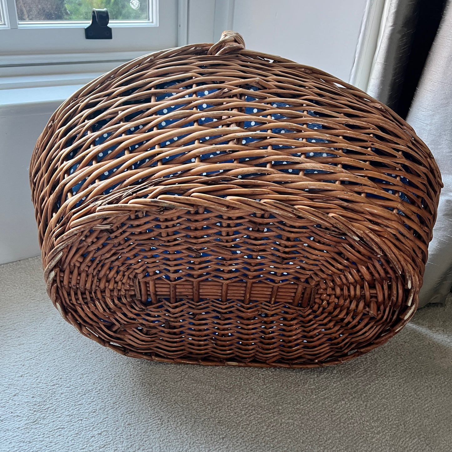 A large wicker basket with a charming blue polka dot fabric lining the interior, adding a playful touch to its rustic exterior