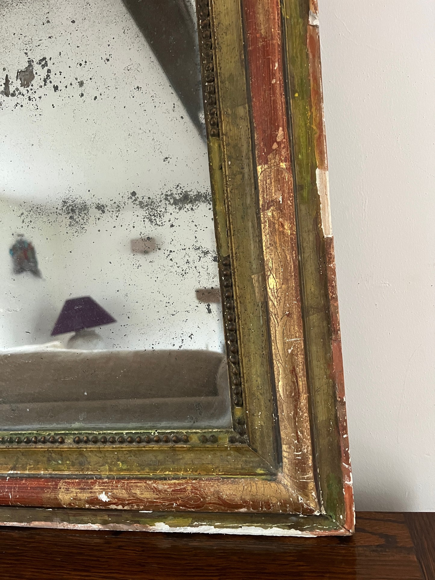 Antique Louis Philippe bevelled mirror dating back to the 19th century, painted in red and green. It has seen a lot of use over time with some of the paintwork missing revealing the plaster frame beneath.