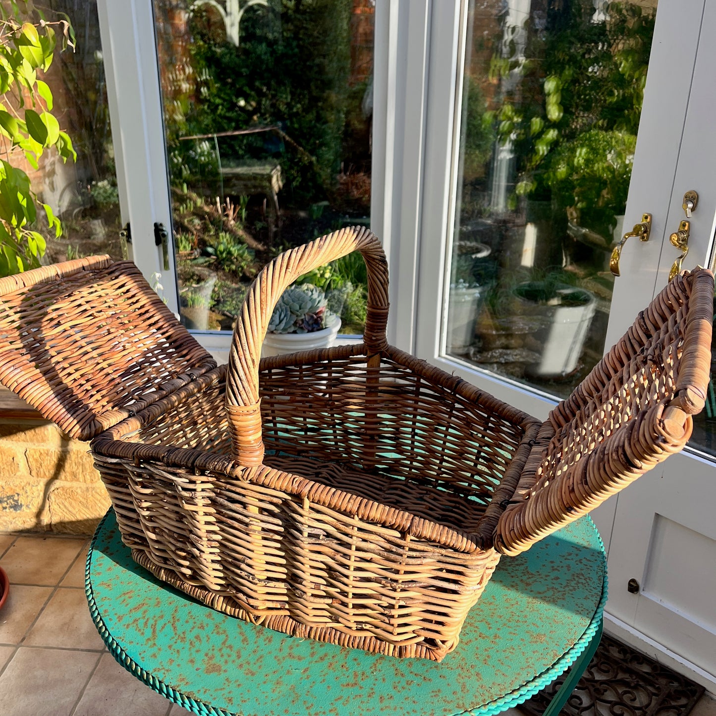 A vintage rustic picnic basket made of woven wicker, featuring two flaps and a sturdy handle on top