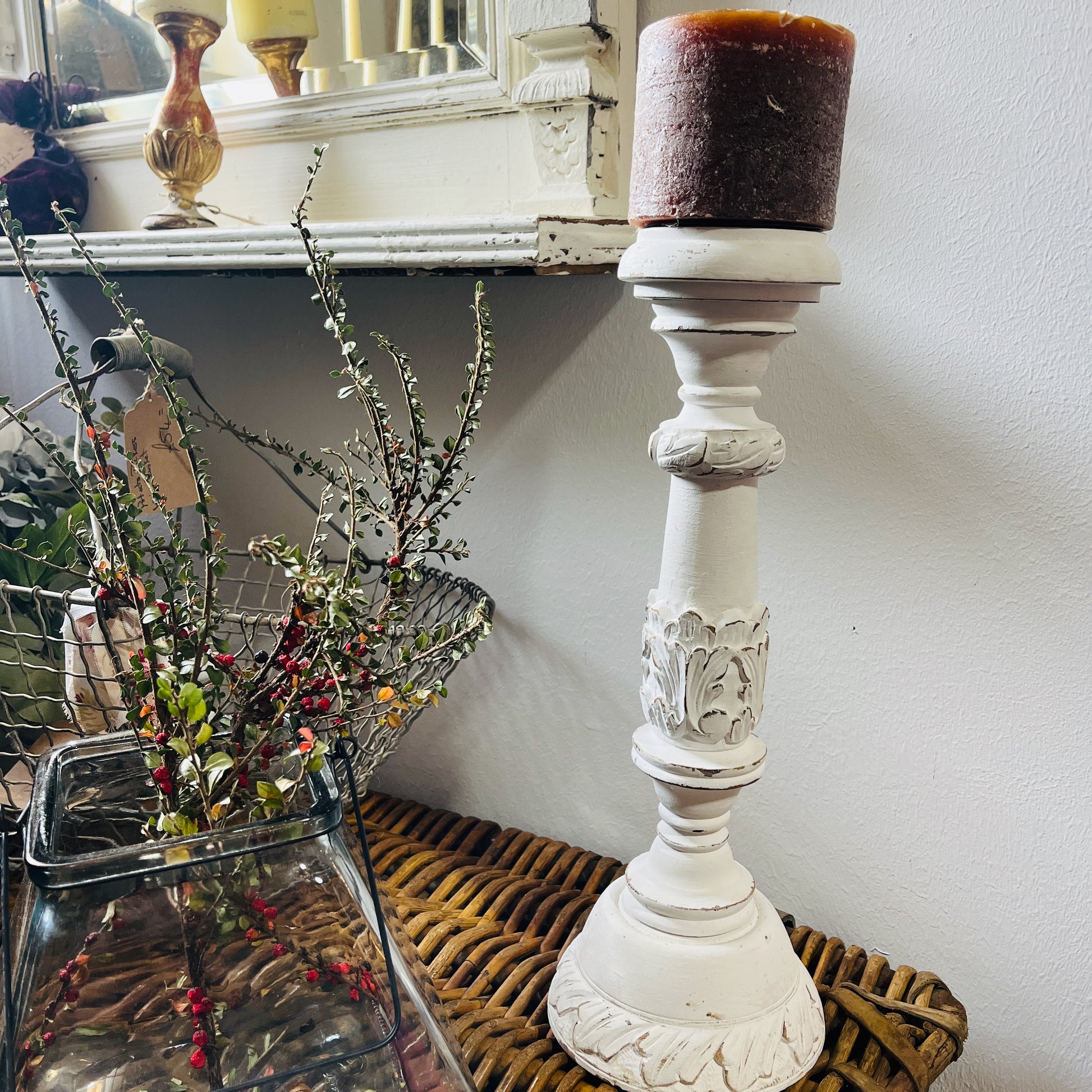 A tall, white candle holder with a decorative design