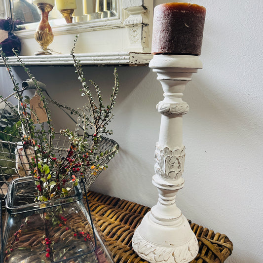 A tall, white candle holder with a decorative design