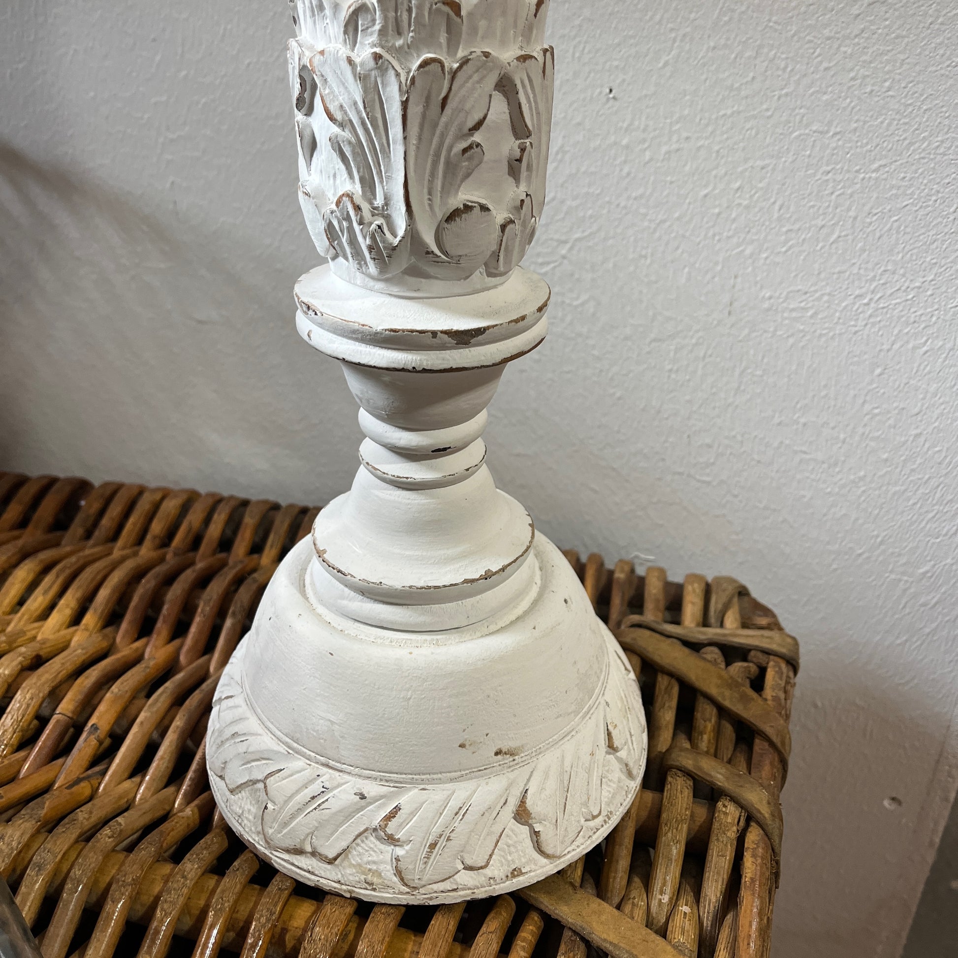 A tall, white candle holder with a decorative design