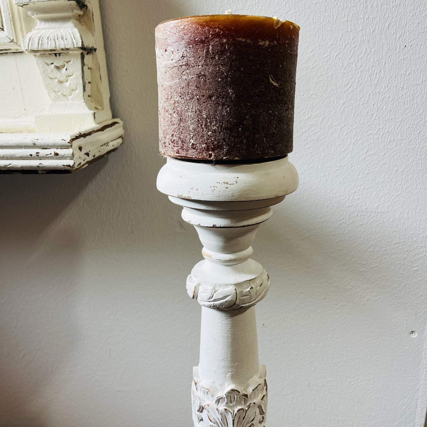 A tall, white candle holder with a decorative design