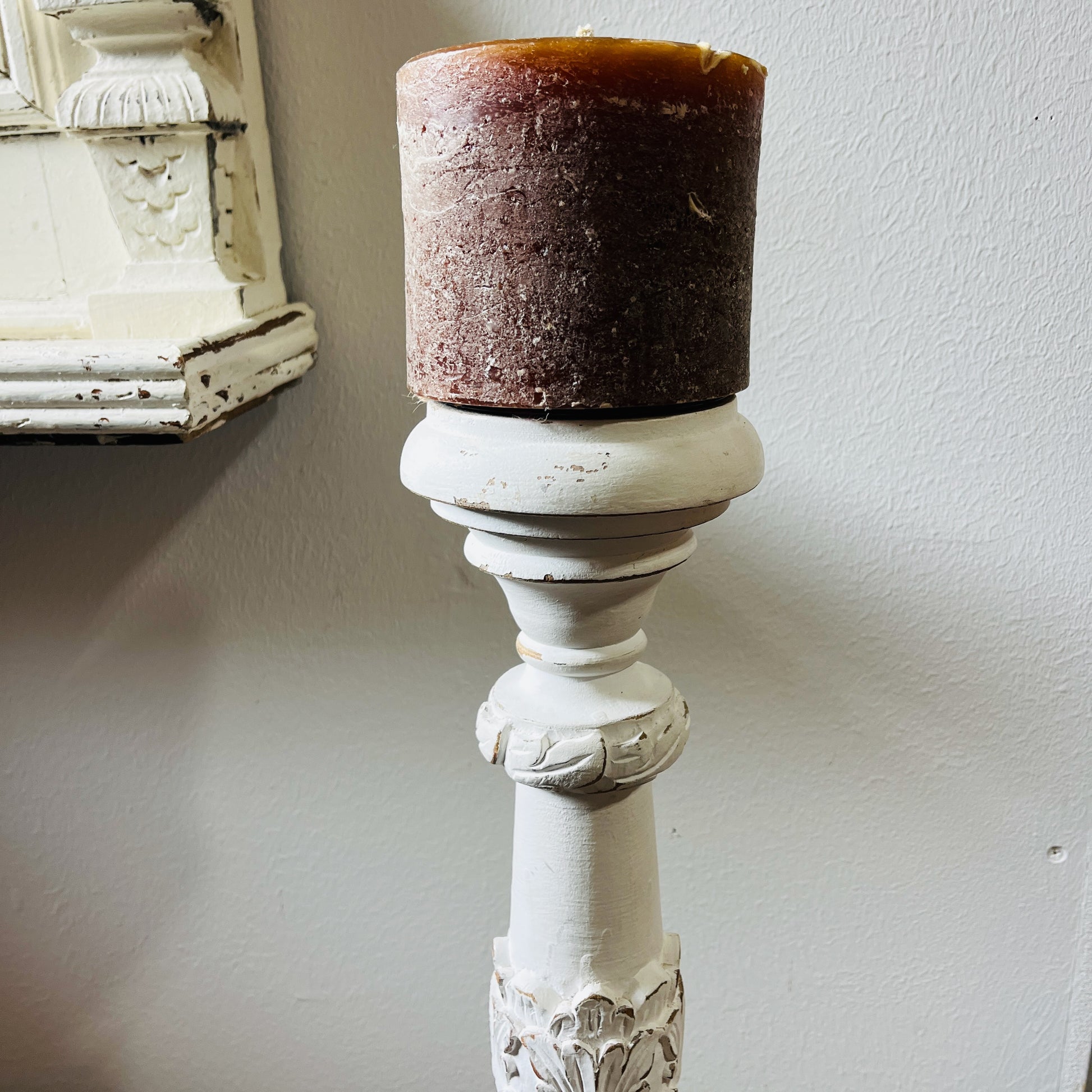 A tall, white candle holder with a decorative design
