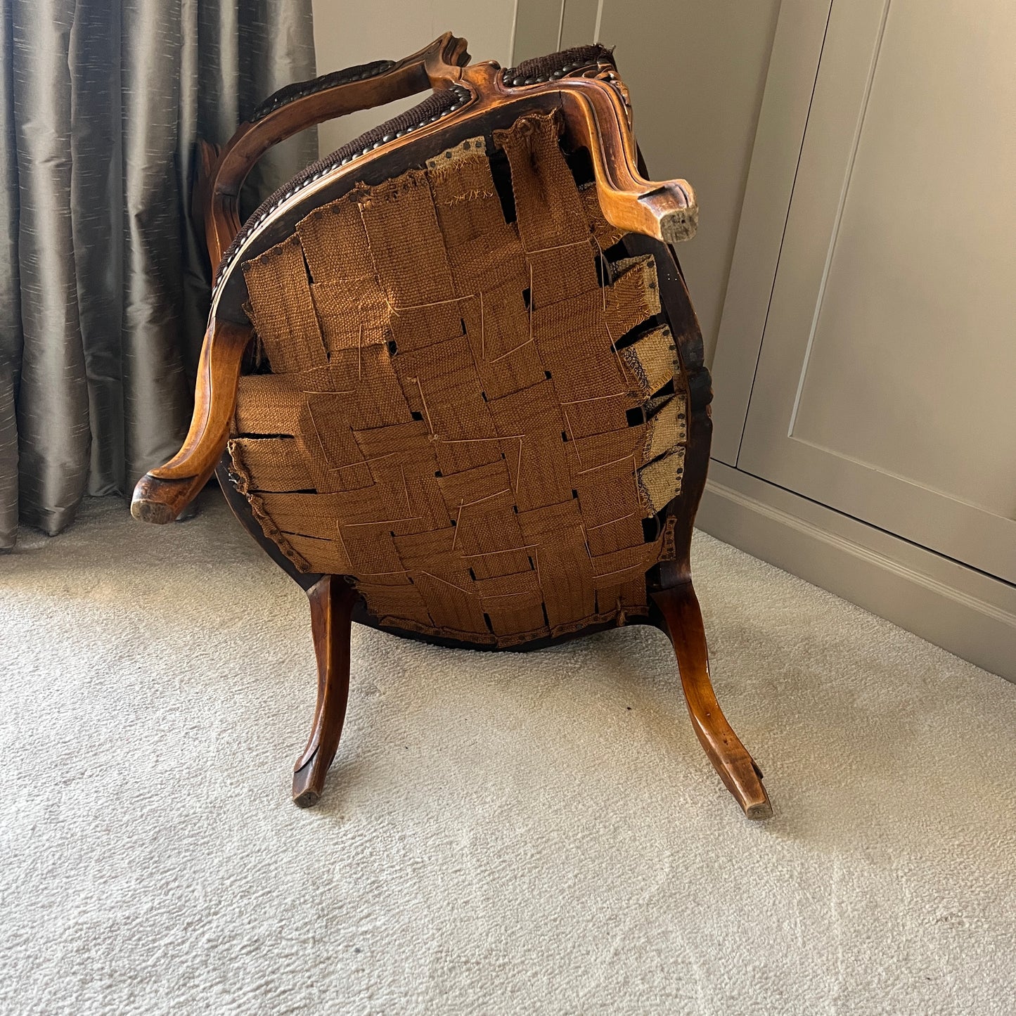 A vintage French carver chair featuring an ornate wooden frame, upholstered with a finely woven tapestry covering that displays intricate patterns and vibrant colours, reflecting classic French artistry and elegance.