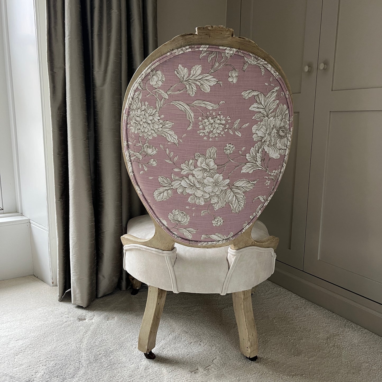 A Victorian occasional chair, recently reupholstered in luxurious cream velvet, with a pink floral back, featuring ornate wooden carvings along the frame and elegant curved legs, exuding a blend of vintage charm and modern sophistication.