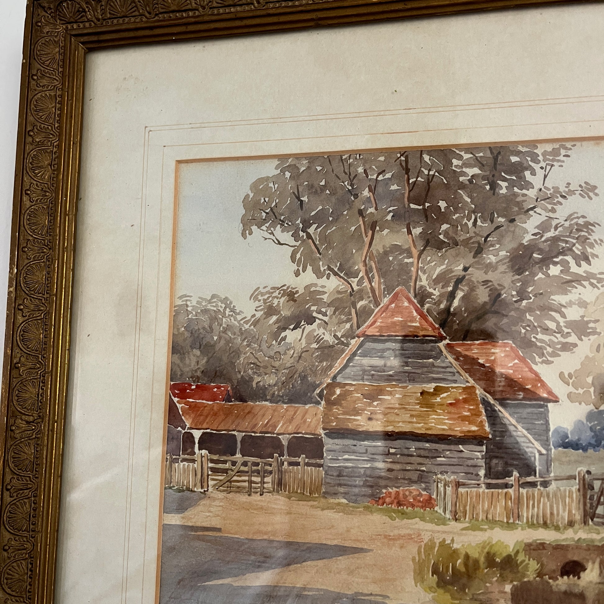 An antique watercolor painting of Loddon Bridge, depicting a serene riverside scene with a stone bridge arching over calm waters. The bridge features weathered stonework, flanked by lush greenery and trees in soft shades of green and brown.  
 Beside the bridge is an old farm building with a terracotta roof. The overall style is detailed yet gentle, characteristic of traditional watercolor techniques.