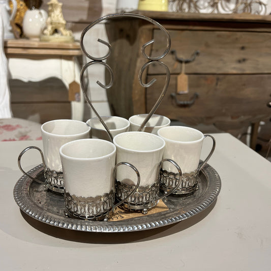 A set of six Wedgwood espresso cups, crafted from fine white china, neatly arranged inside a  decorative metal case with a handle. The case rests on a tray, showcasing the cups' delicate design