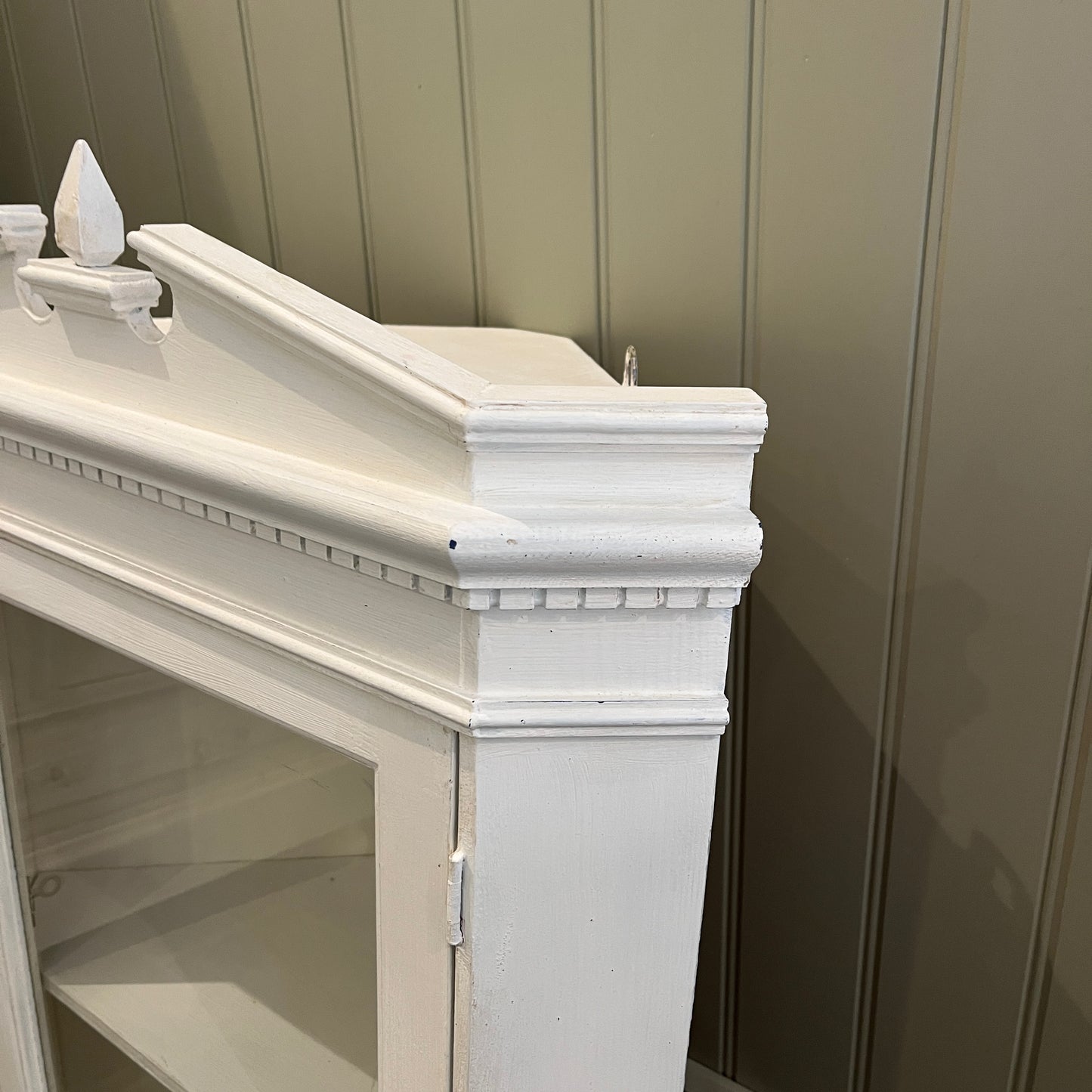 A white wooden corner cabinet designed for bathroom use, which fits into a corner, with a single door and interior shelves for practical storage, offering a clean and classic look.