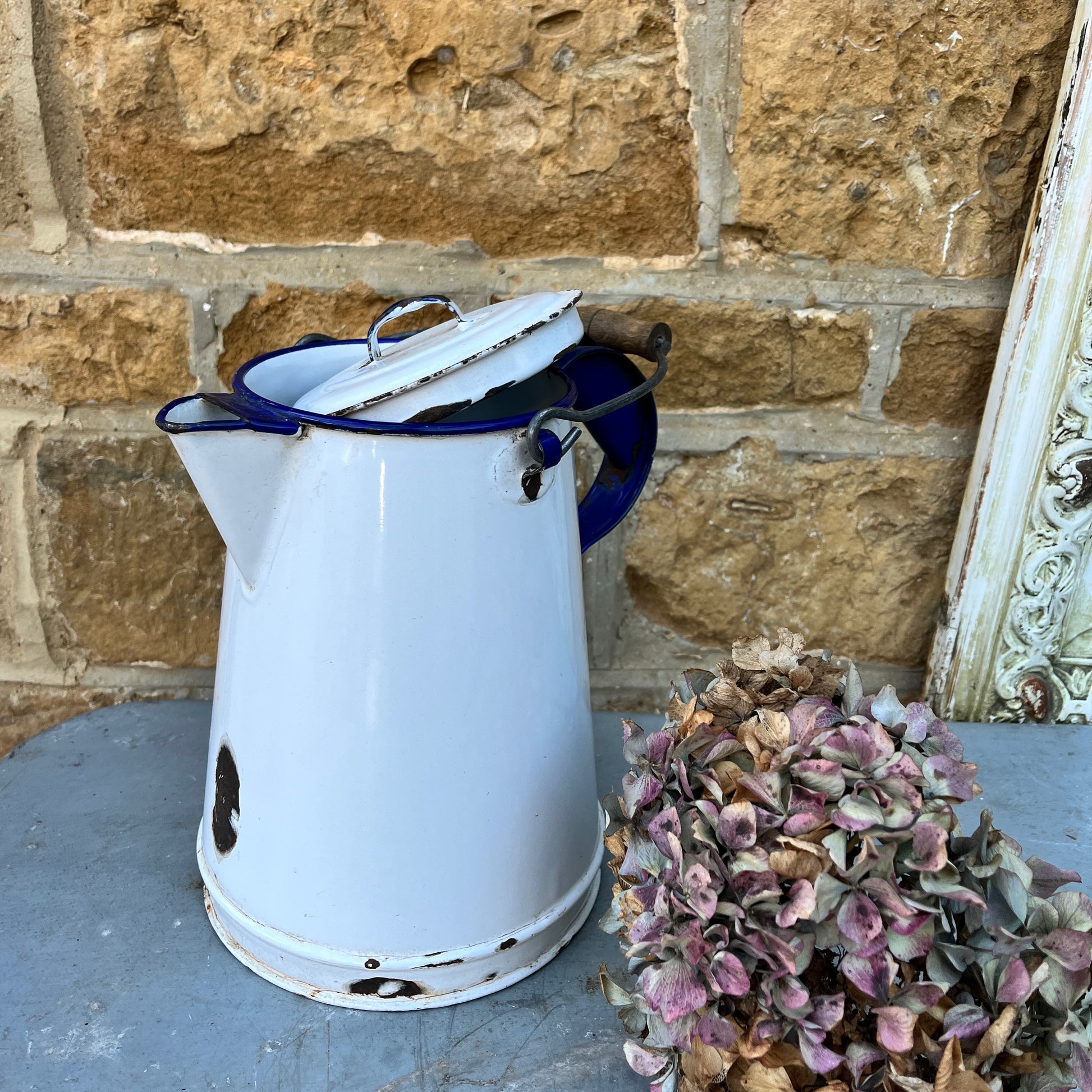 Vintage white enamel jug showing wear and tear with a black metal/wood handle and separate lid