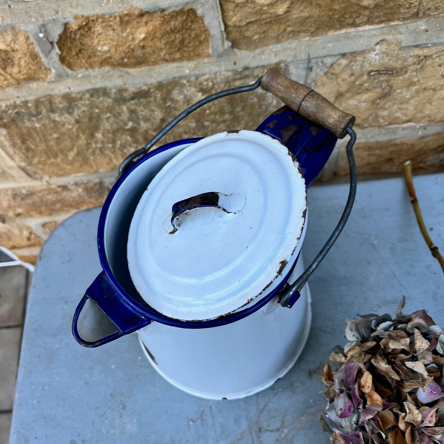 Vintage white enamel jug showing wear and tear with a black metal/wood handle and separate lid
