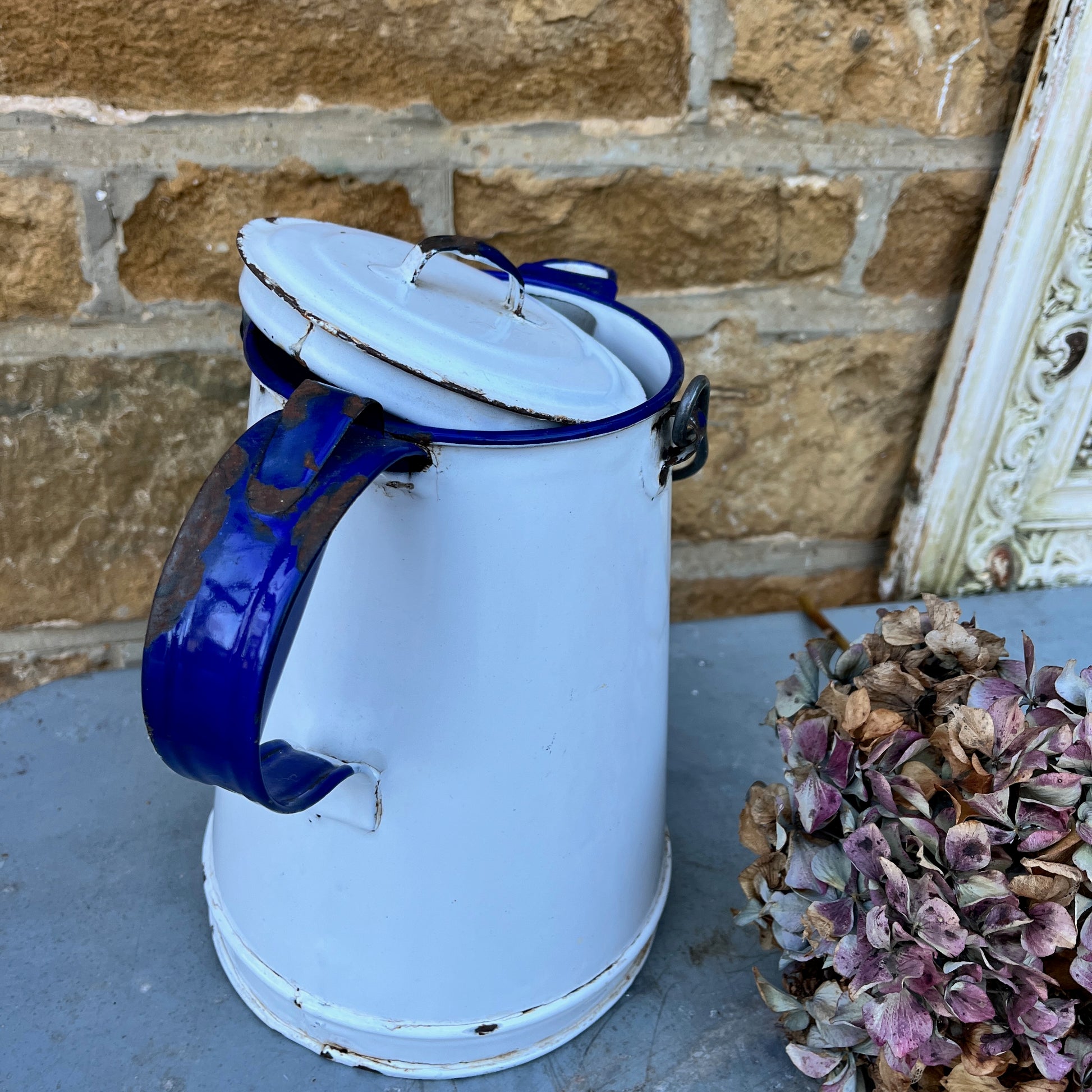Vintage white enamel jug showing wear and tear with a black metal/wood handle and separate lid