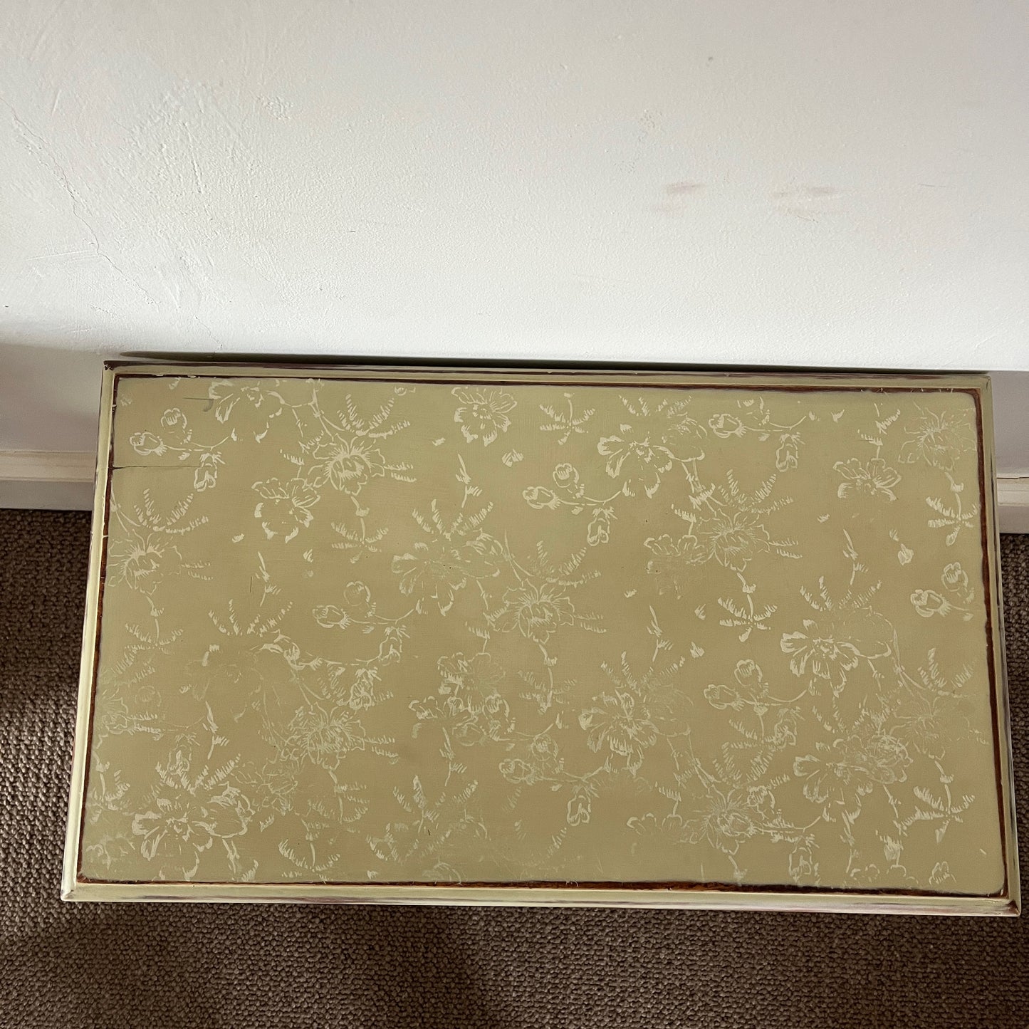 Small rustic table painted in muted yellow, featuring a distressed finish and a stencilled top, adding a pop of colour and vintage charm to any space