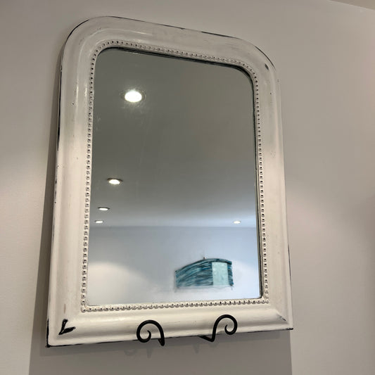 A 20th-century bathroom mirror with a wooden frame, painted white and intentionally distressed to reveal subtle wear and texture, offering a vintage, shabby-chic charm with a rectangular shape and slightly weathered edges.