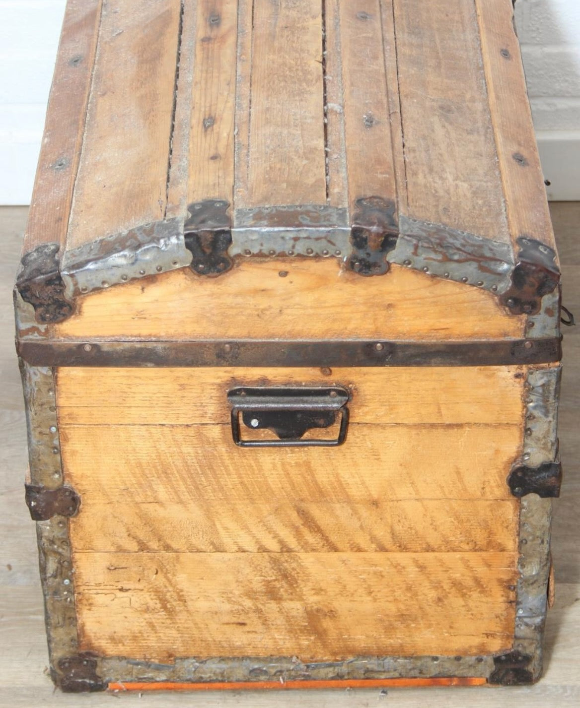 Antique steamer trunk with a sturdy rectangular form, metal hardware, and a weathered exterior showing age and travel wear.