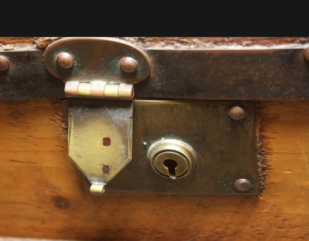 Antique steamer trunk with a sturdy rectangular form, metal hardware, and a weathered exterior showing age and travel wear.