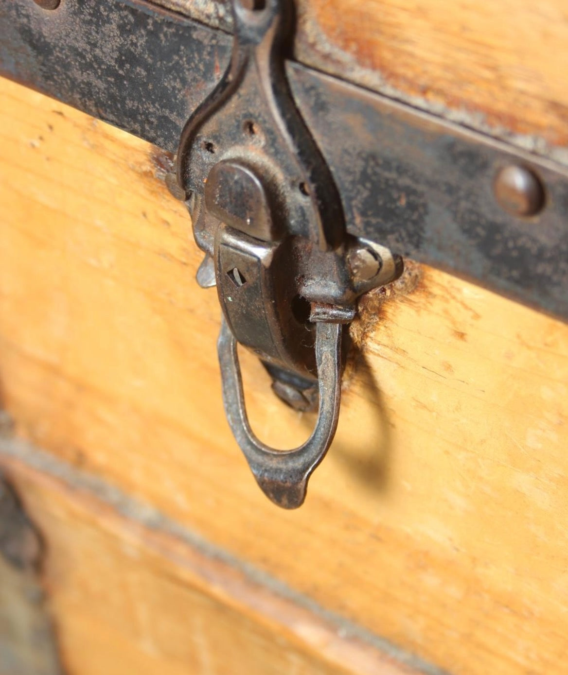 Antique steamer trunk with a sturdy rectangular form, metal hardware, and a weathered exterior showing age and travel wear.