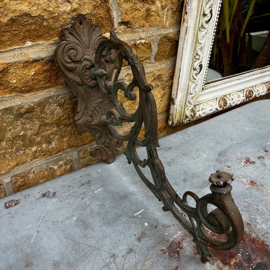 Decorative metal bracket with intricate designs on a textured surface