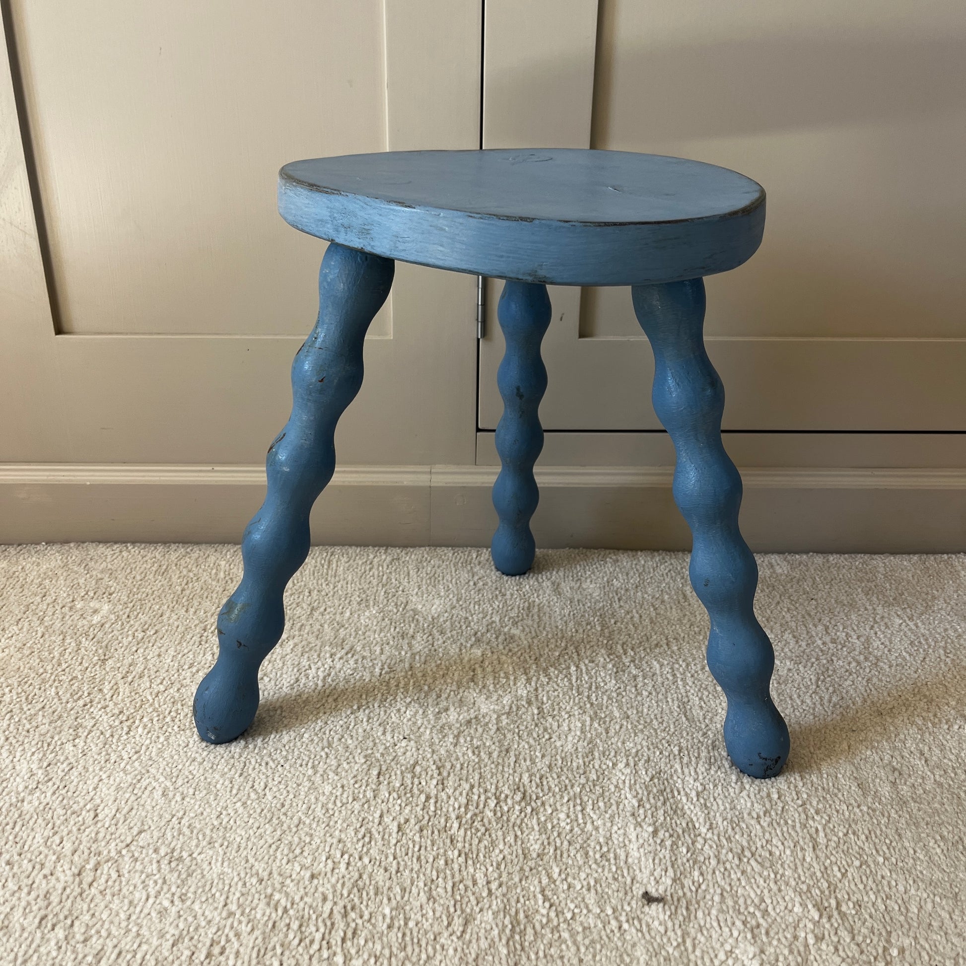 Wooden stool with three turned bobbin-style legs - painted blue and distressed.