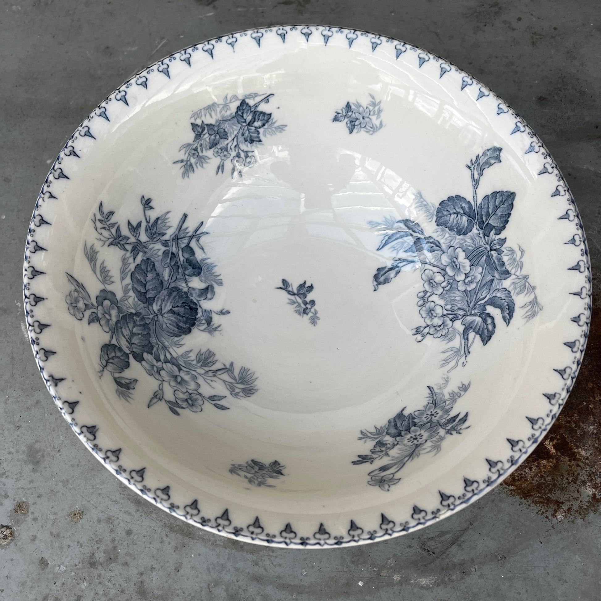 An antique French blue and white transferware bowl featuring an intricate floral and scenic pattern in classic cobalt blue on a white ceramic background