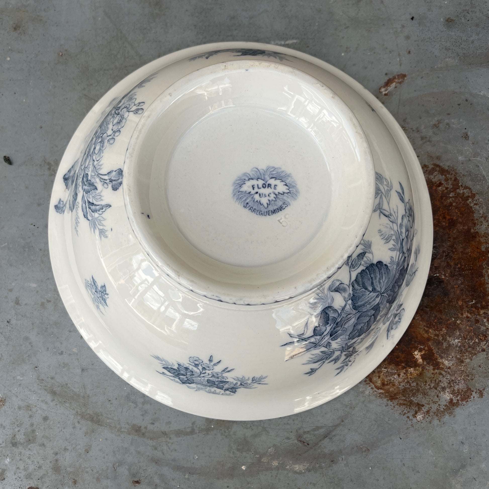 An antique French blue and white transferware bowl featuring an intricate floral and scenic pattern in classic cobalt blue on a white ceramic background
