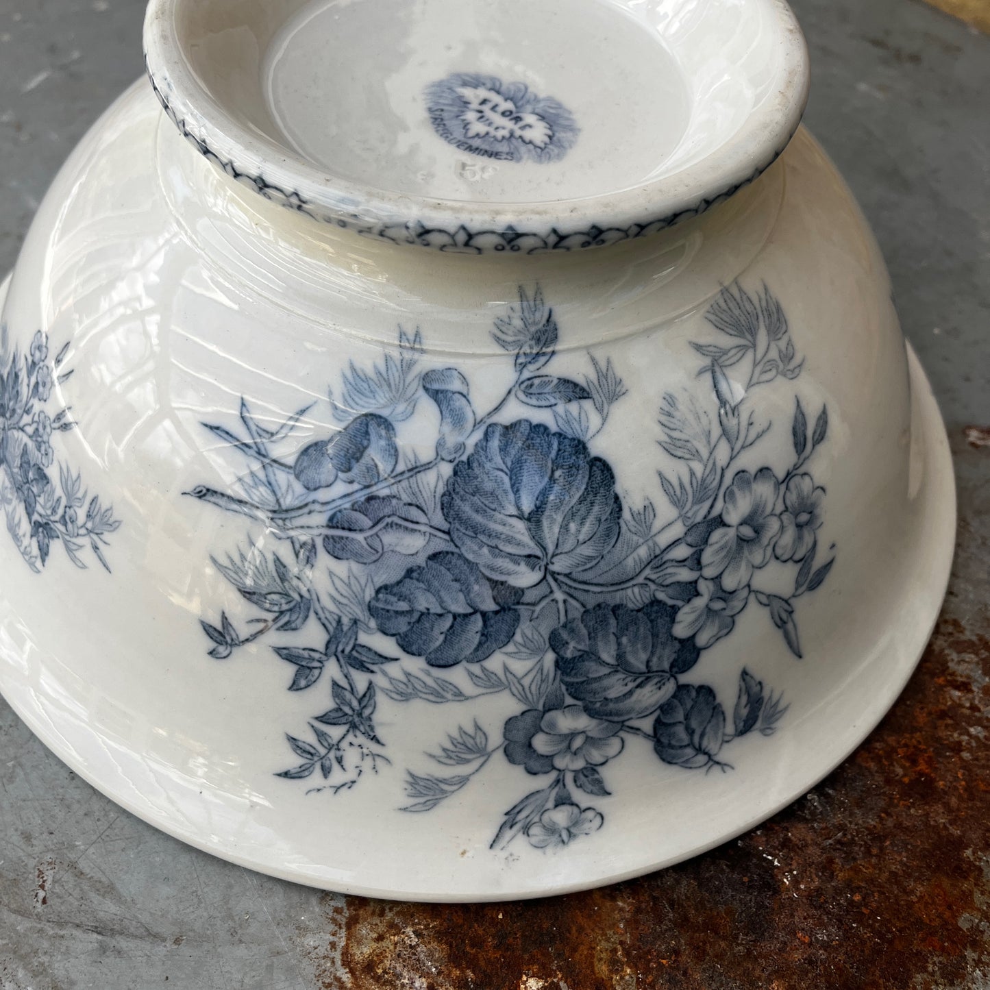 An antique French blue and white transferware bowl featuring an intricate floral and scenic pattern in classic cobalt blue on a white ceramic background
