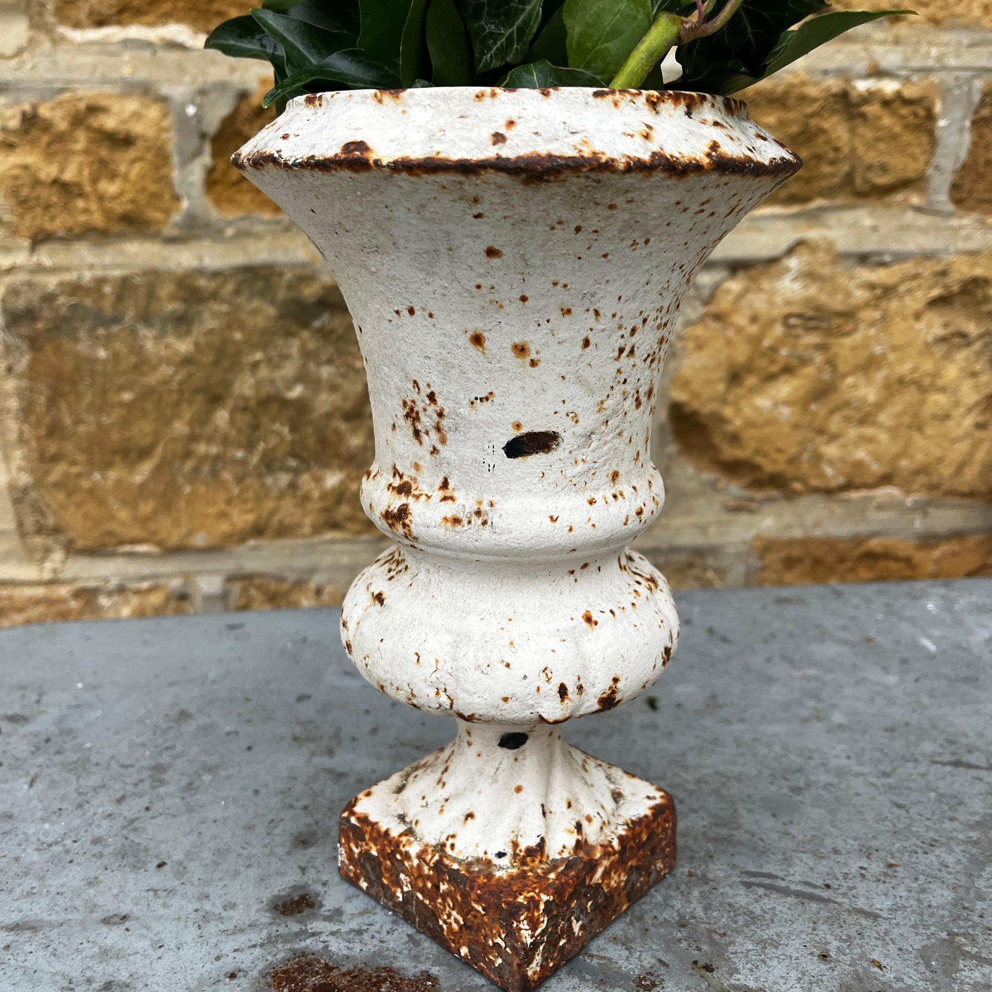 Pair of vintage Camana urns in a white finish. The urns feature classic shapes with decorative detailing and a weathered, aged patina, giving them a rustic, antique charm.