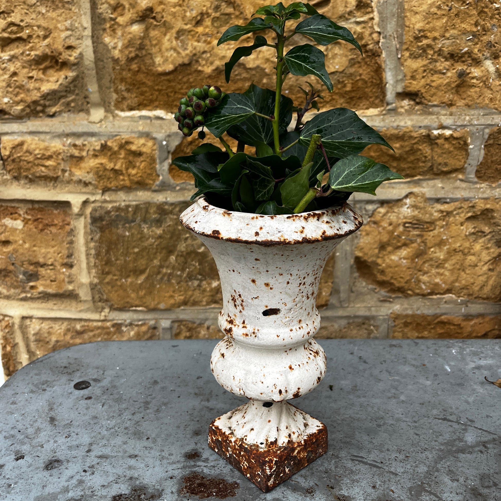 Pair of vintage Camana urns in a white finish. The urns feature classic shapes with decorative detailing and a weathered, aged patina, giving them a rustic, antique charm.