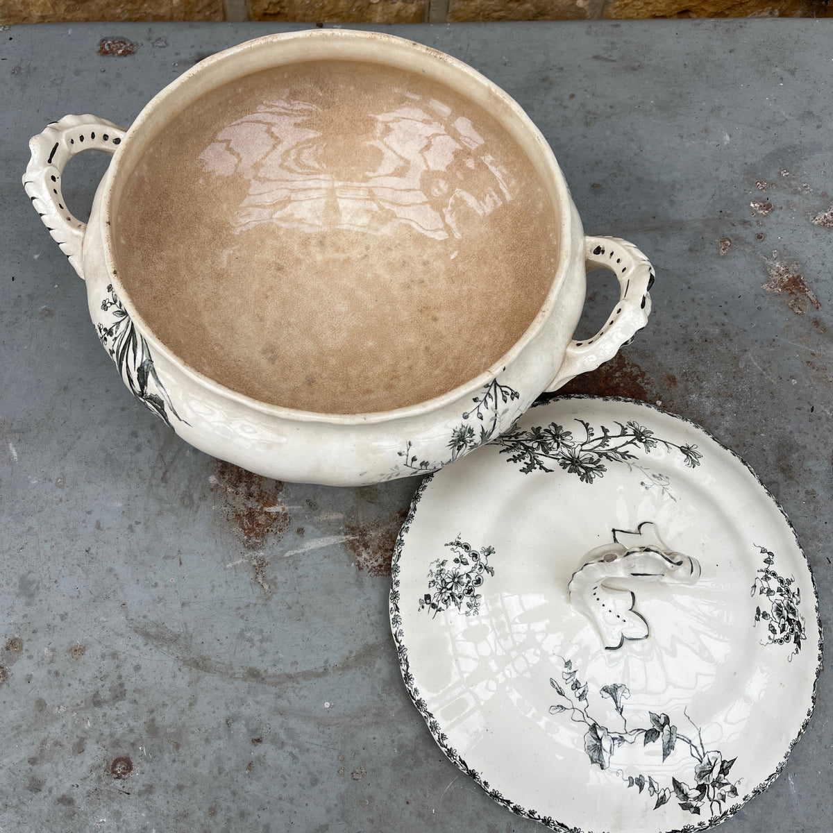 A white ceramic lidded tureen with dark green floral toile de Jouy patterns, on both the tureen and the lid.