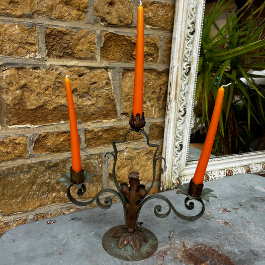 An ornate vintage three-arm metal candelabra with a naturally aged green patina and rusted floral candle holders