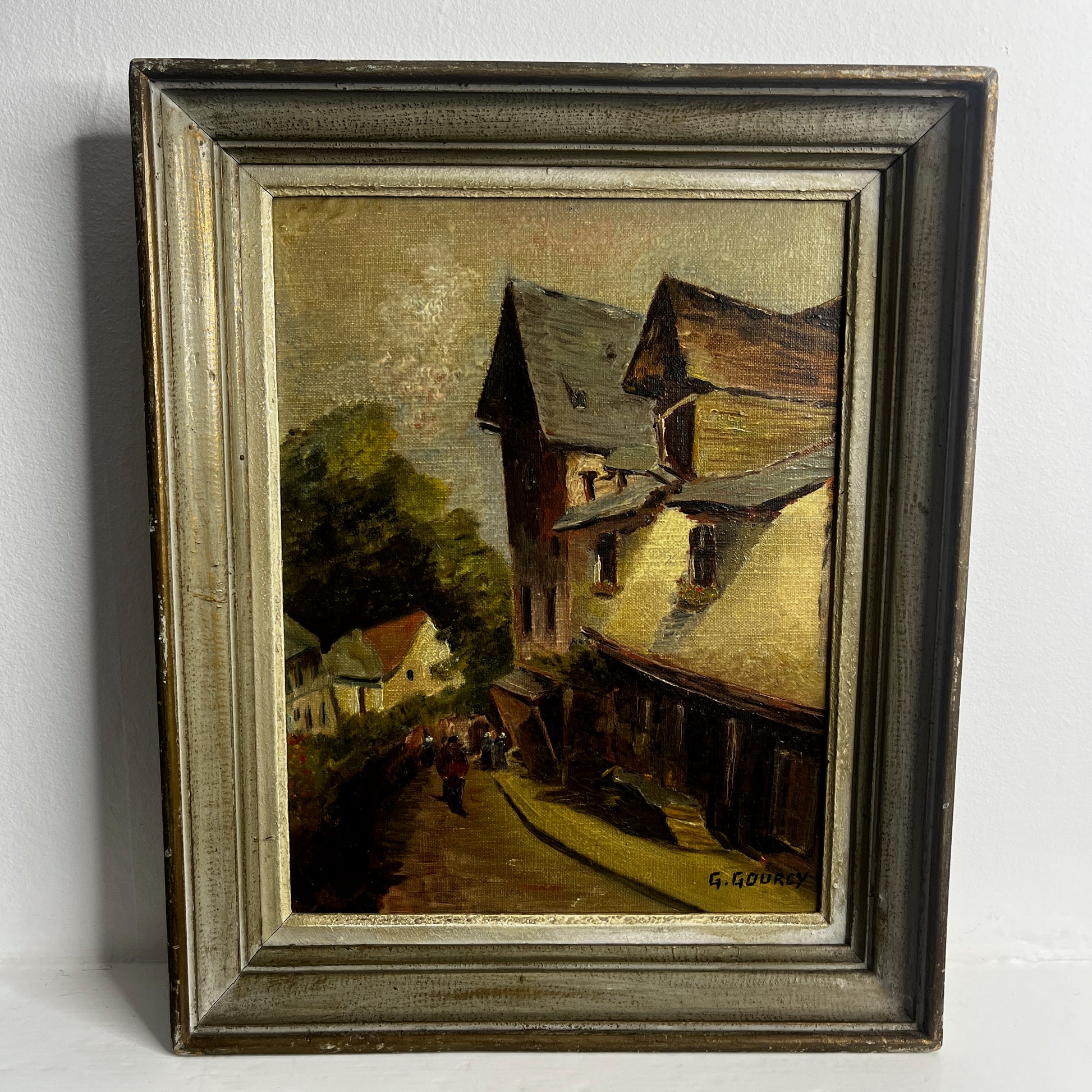 Framed painting of a village scene  in Dinan, France with houses and trees.