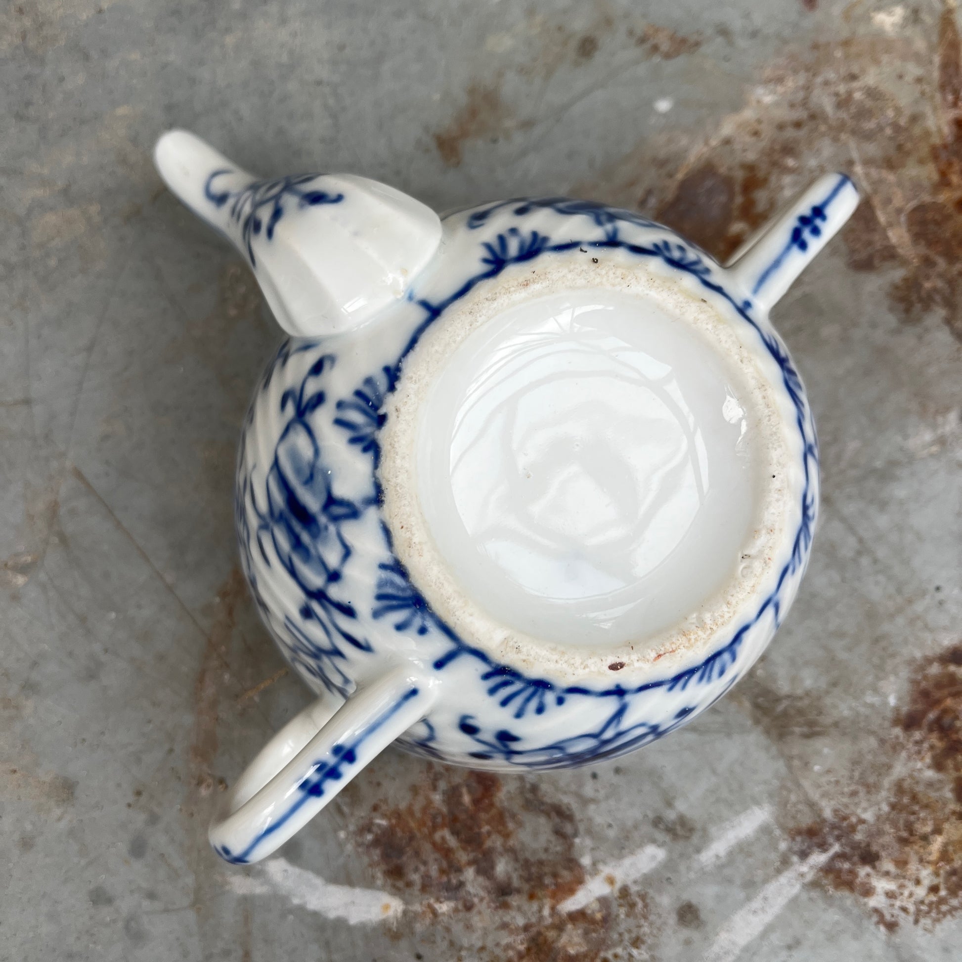 Blue and white ceramic drinking cup on a stone surface with a natural background