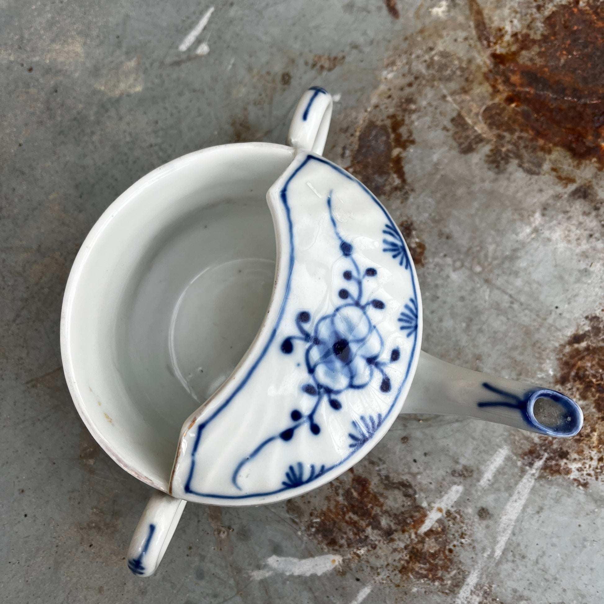 Blue and white ceramic drinking cup on a stone surface with a natural background