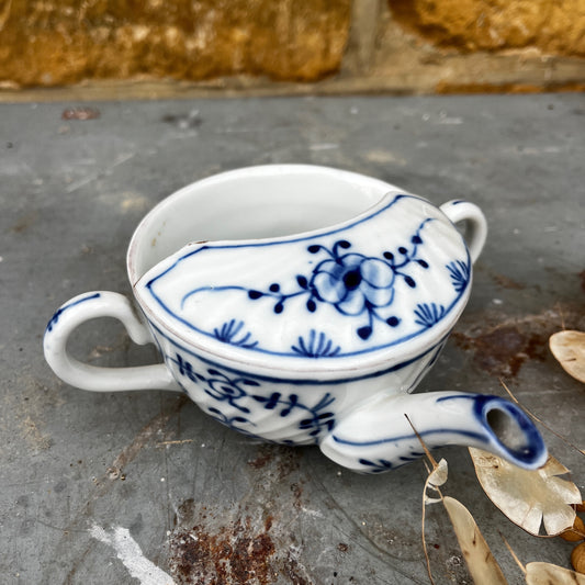 Blue and white ceramic drinking cup on a stone surface with a natural background
