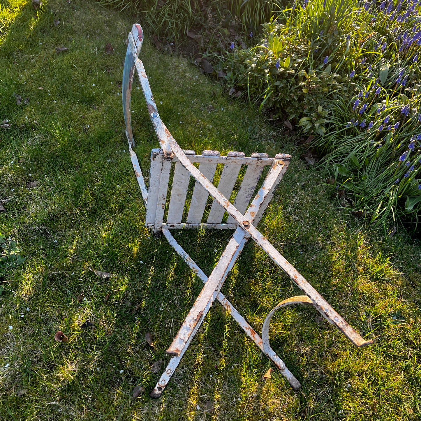 Vintage French bistro chairs with wooden slatted seats and backs, featuring metal folding frames painted in turquoise and pink.

