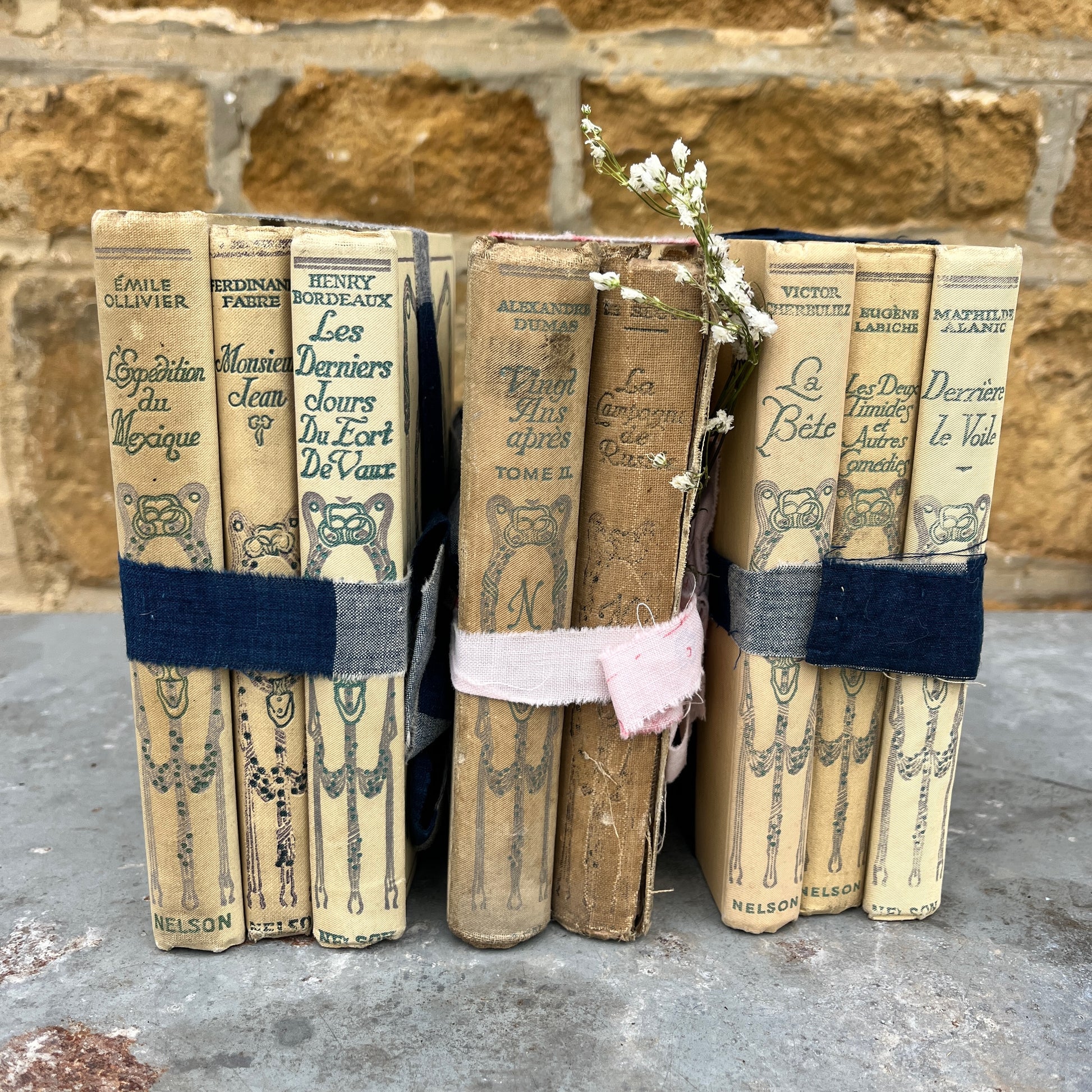 Three vintage-looking books tied with ribbons and small flowers 
