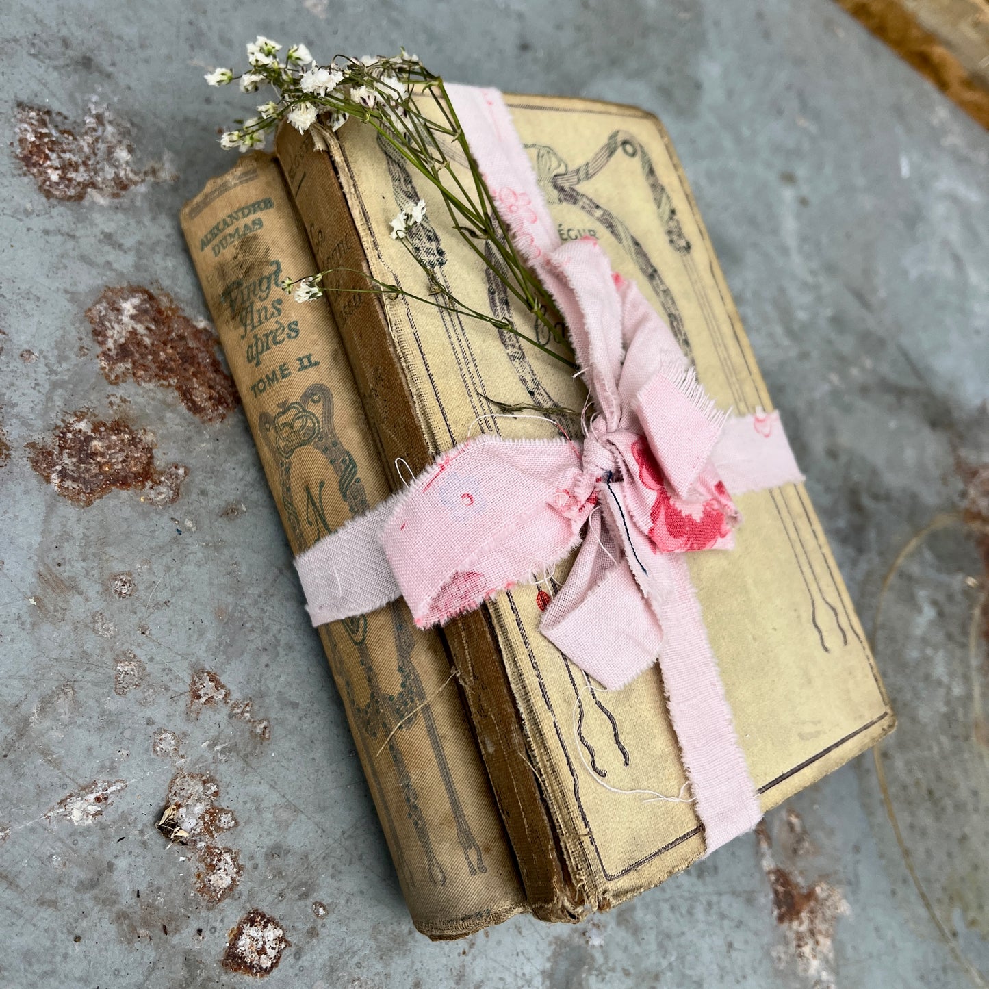 Three vintage-looking books tied with ribbons and small flowers 