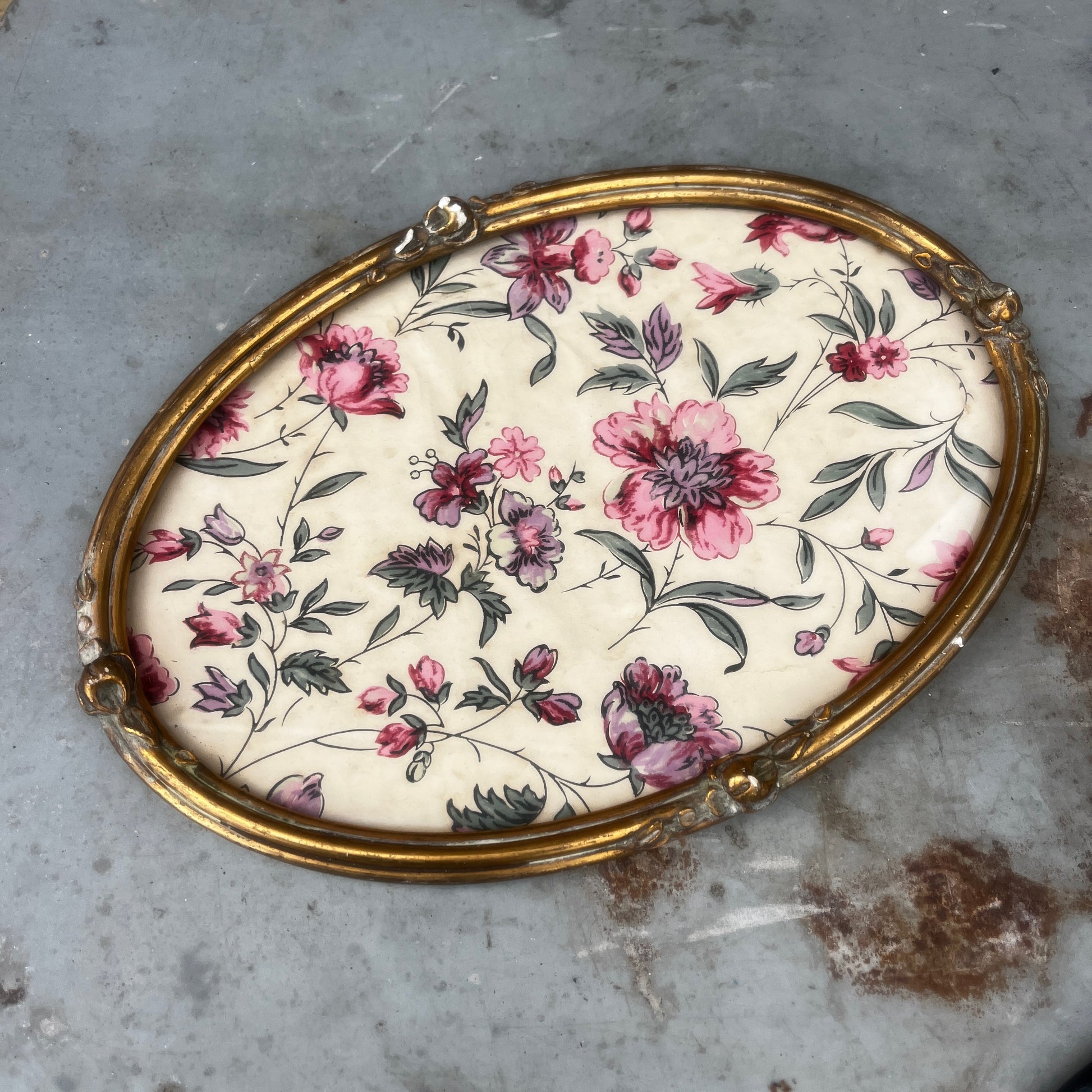 A vintage oval French gilded tray or picture frame with an ornate raised border and distressed gold finish