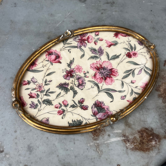 A vintage oval French gilded tray or picture frame with an ornate raised border and distressed gold finish