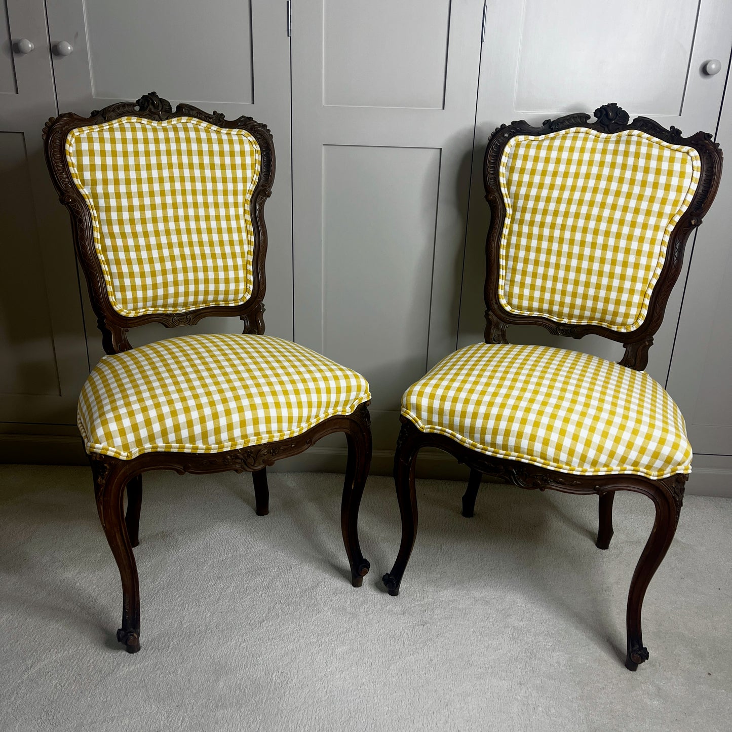 Pair of French salon chairs, newly upholstered in mustard gingham fabric, featuring elegant wooden frames and classic curved backs.
