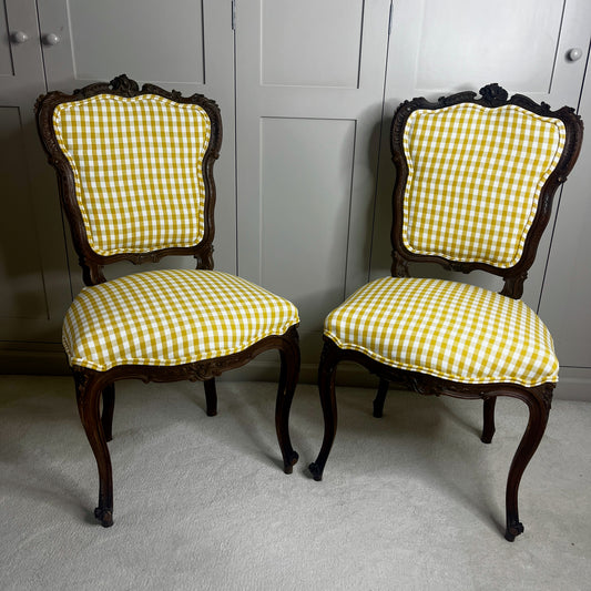 Pair of French salon chairs, newly upholstered in mustard gingham fabric, featuring elegant wooden frames and classic curved backs.
