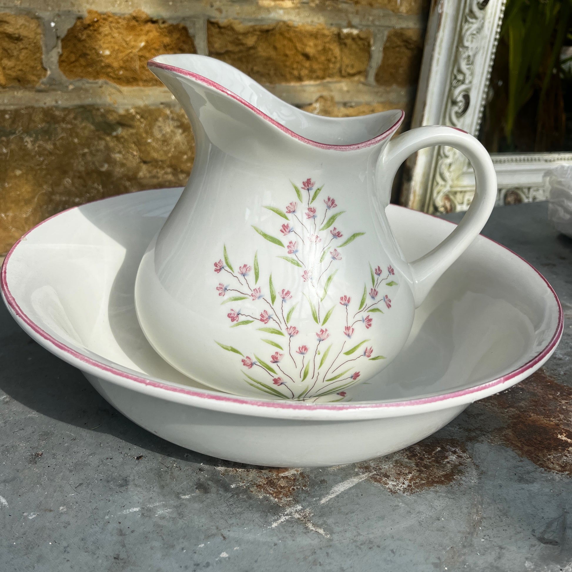 A vintage French Moulin des Loups ceramic wash basin and matching pitcher featuring a classic white glazed finish with delicate pink and green floral decoration.