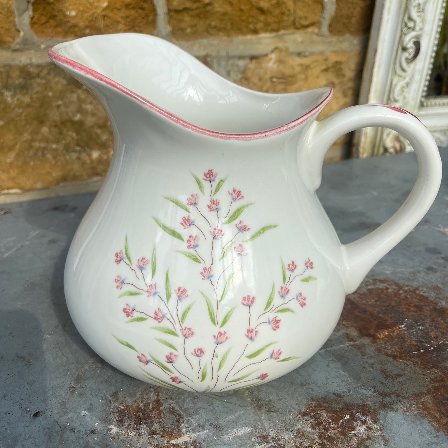A vintage French Moulin des Loups ceramic wash basin and matching pitcher featuring a classic white glazed finish with delicate pink and green floral decoration.