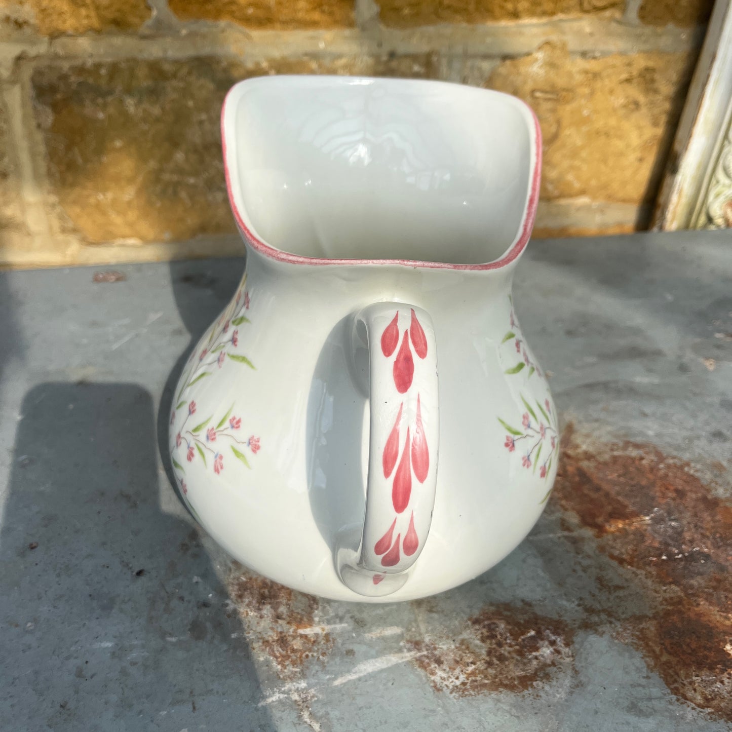 A vintage French Moulin des Loups ceramic wash basin and matching pitcher featuring a classic white glazed finish with delicate pink and green floral decoration.