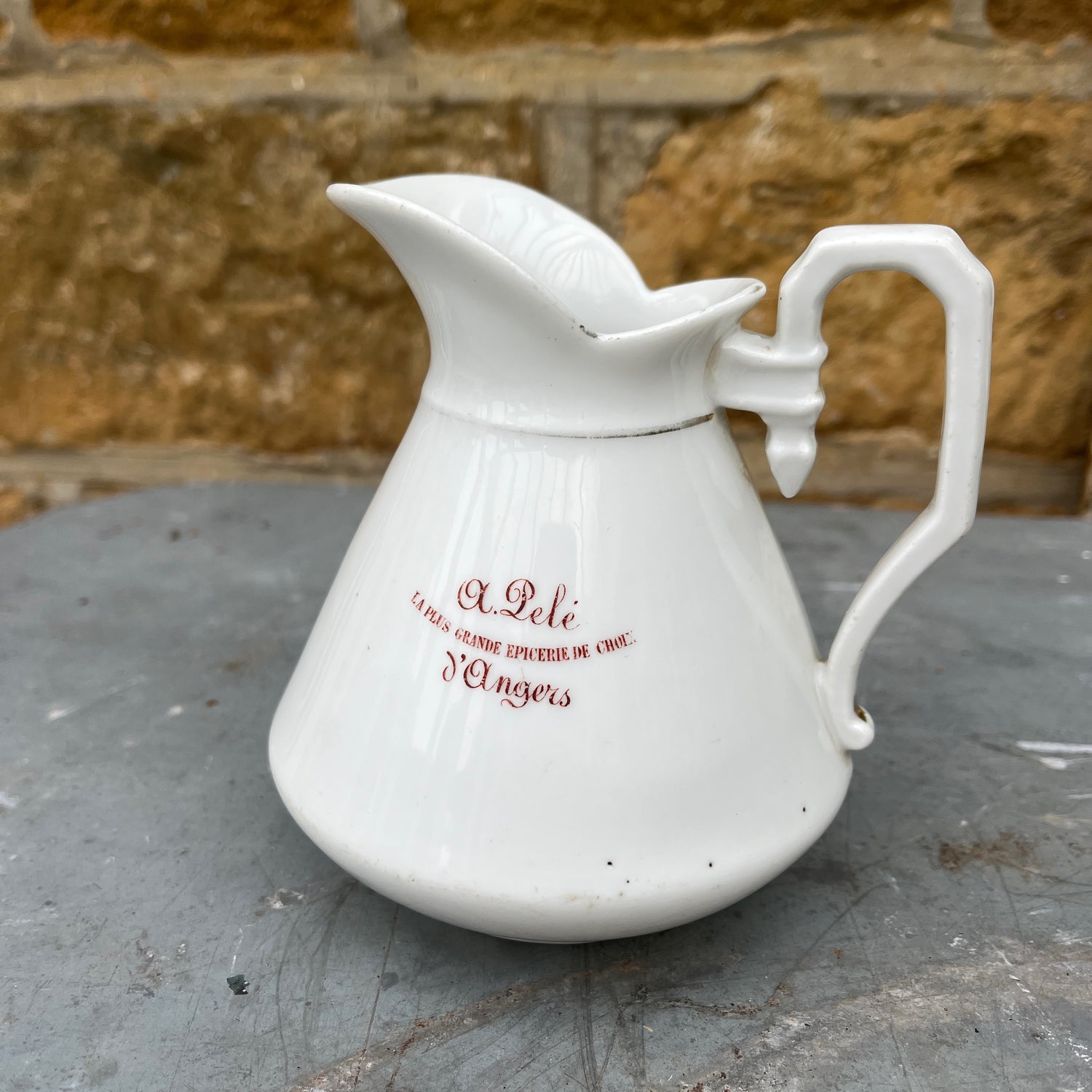French vintage jug with a white-colored body and maroon writing detail. The jug has a classic rounded shape and a slightly aged finish, showcasing rustic, antique French charm.