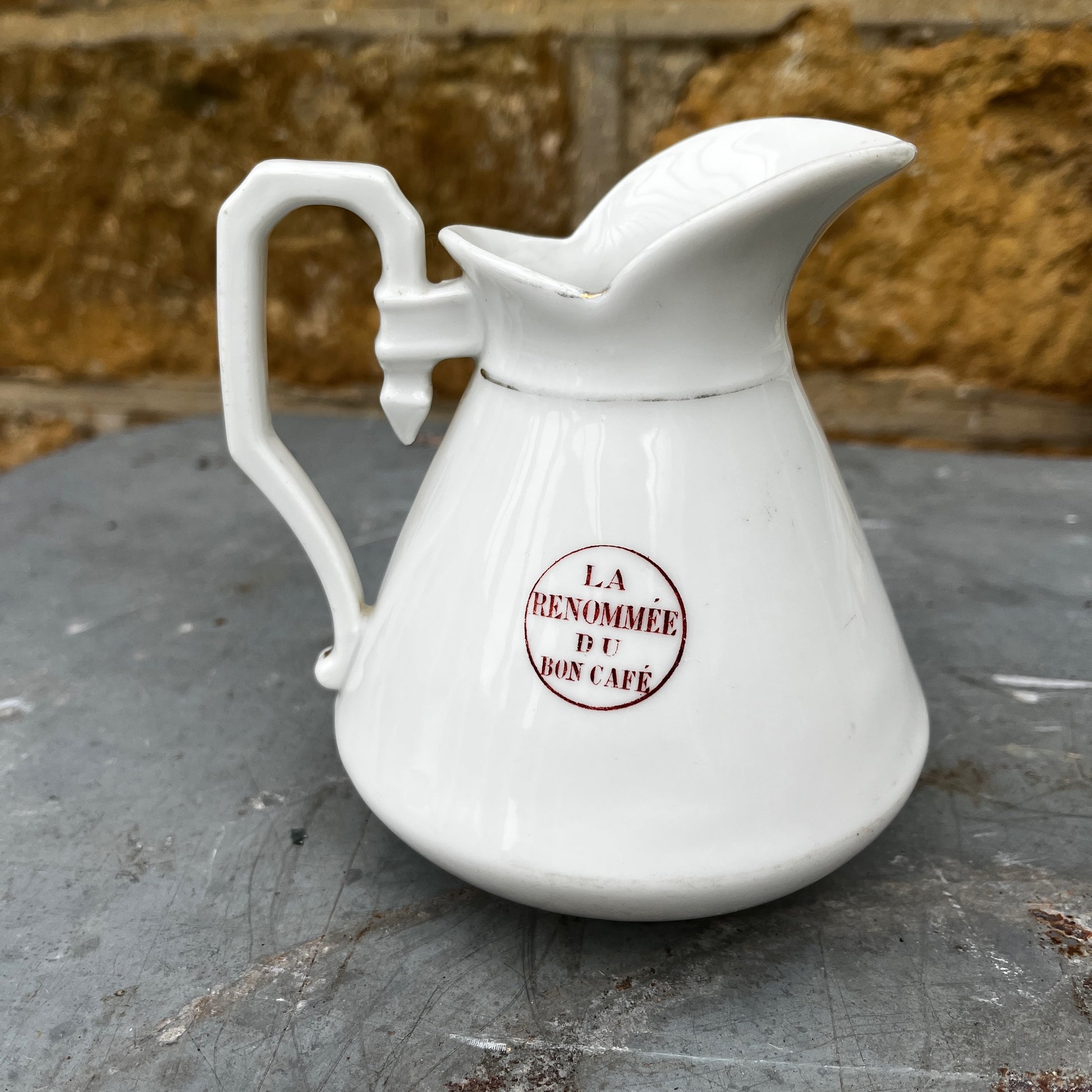 French vintage jug with a white-colored body and maroon writing detail. The jug has a classic rounded shape and a slightly aged finish, showcasing rustic, antique French charm.