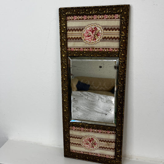 intage French decorative mirror with a carved giltwood frame and floral fabric panels.