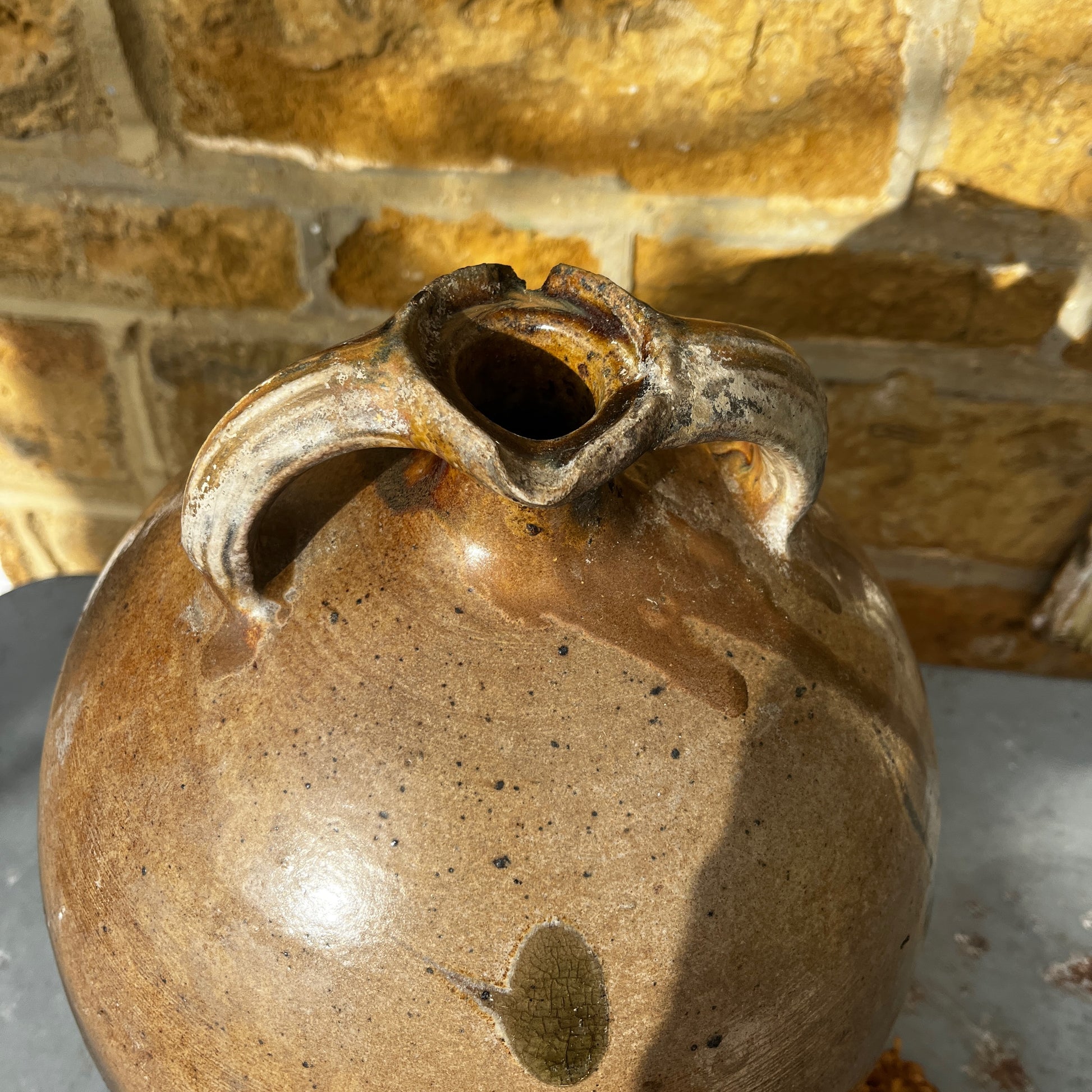 
Large vintage French stoneware oil jar with a rounded body, narrow neck, and earthy glaze, showing natural patina and rustic texture typical of traditional French farmhouse pottery.
