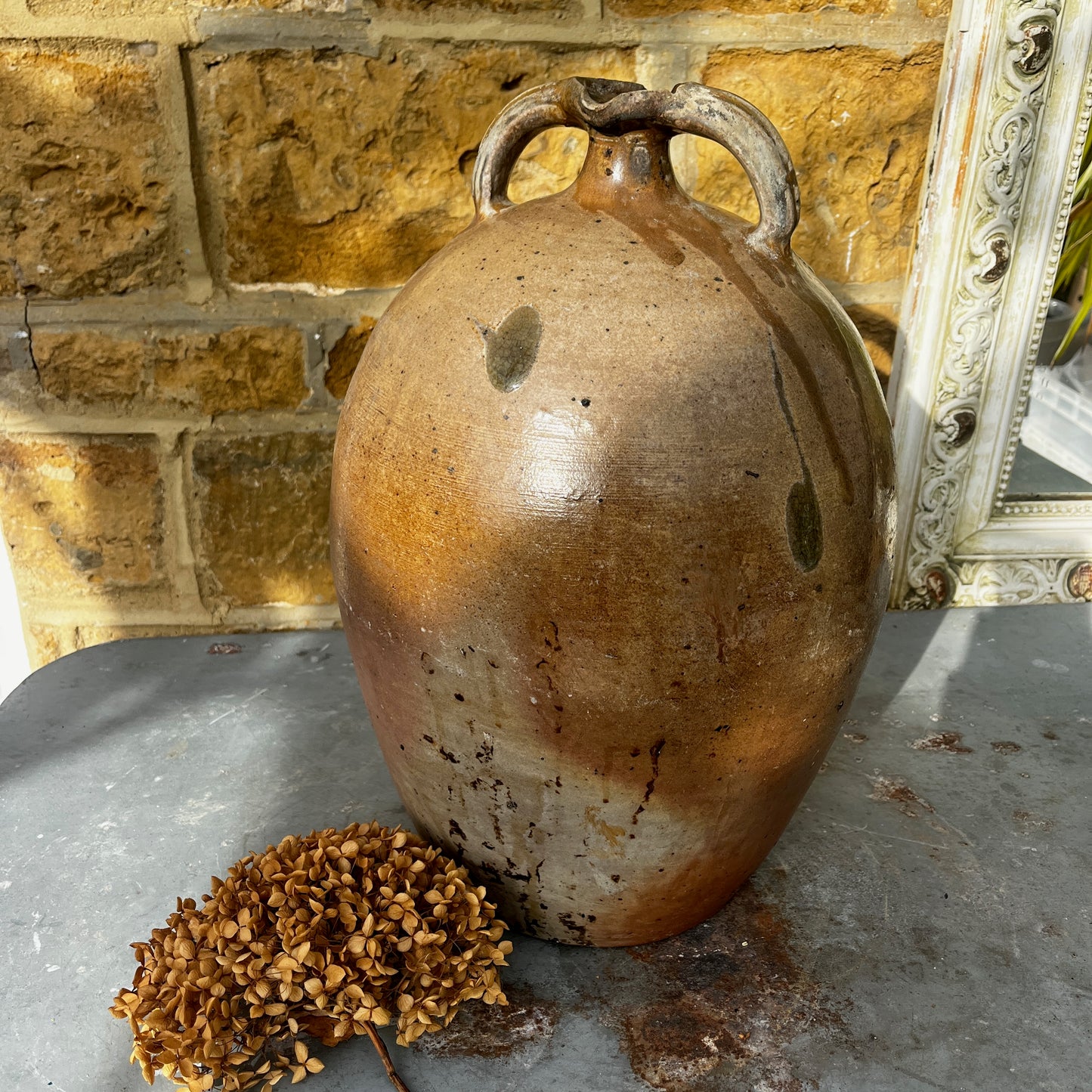 Large vintage French stoneware oil jar with a rounded body, narrow neck, and earthy glaze, showing natural patina and rustic texture typical of traditional French farmhouse pottery.

