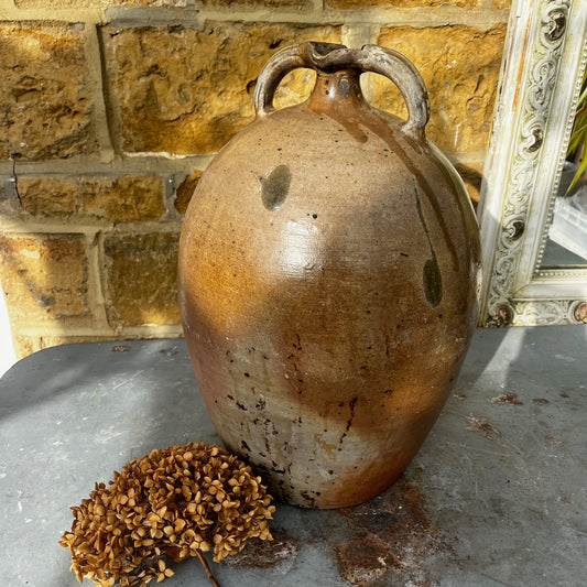 Large vintage French stoneware oil jar with a rounded body, narrow neck, and earthy glaze, showing natural patina and rustic texture typical of traditional French farmhouse pottery.
